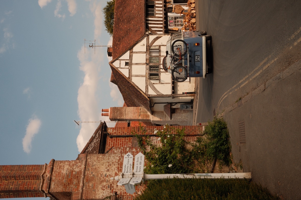 A Surrey village street at golden hour, timber-framed houses and a classic campervan